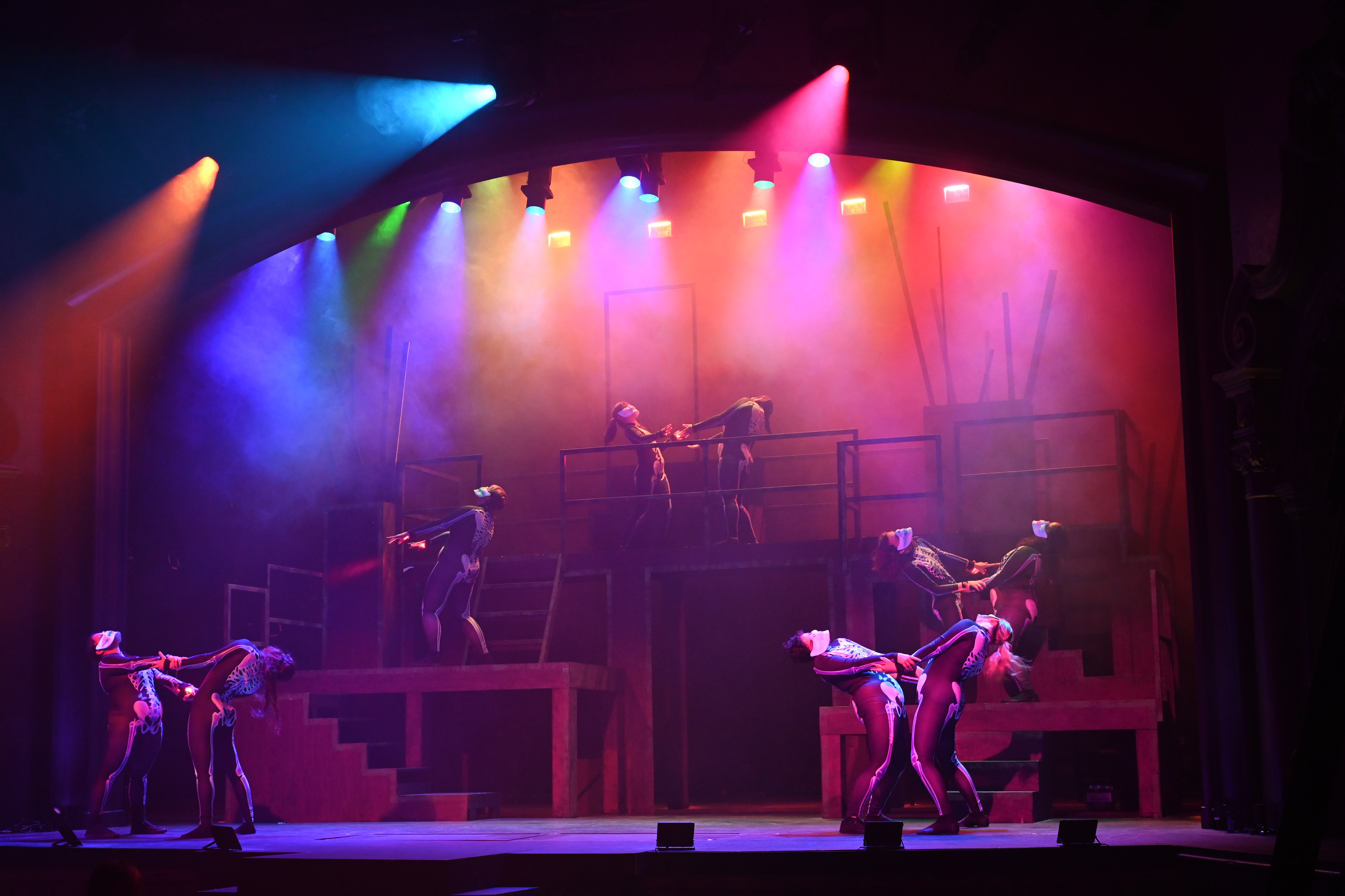 People dressed as skeletons dancing under multicolored lights